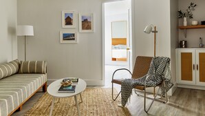 A modern living room with a sofa, a patterned armchair, a coffee table, and a bookshelf. -  Parker Beach Lodge (South Yarmouth)