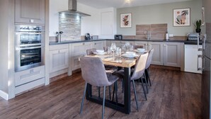 A modern kitchen with built-in ovens, a central island with seating, and a dining area set for four.