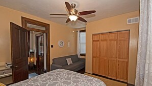 A bedroom with a bed, a ceiling fan, a wooden wardrobe, and a sofa. - Updated Victorian - Serene Backyard + City Access (Pittsburgh)