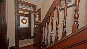 A wooden staircase with a glass door entrance, a doormat, and a framed picture on the wall. - Updated Victorian - Serene Backyard + City Access (Pittsburgh)