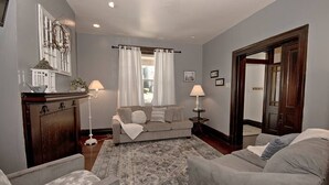 A living room with a grey sofa, two armchairs, a patterned rug, a wooden cabinet, and a white lamp. - Updated Victorian - Serene Backyard + City Access (Pittsburgh)