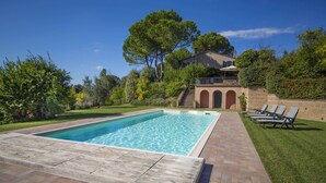 A rectangular swimming pool with a tiled deck, surrounded by a well-maintained lawn and a brick wall. - MY TUSCANY VILLA: Absolute privacy, between pine and olive trees (Palaia)