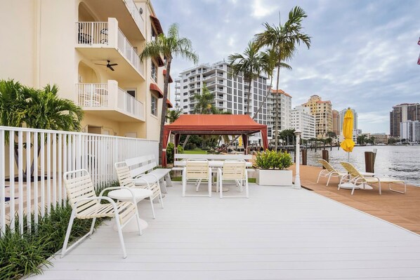 A waterfront balcony with outdoor seating, a covered area, and a view of the city skyline.