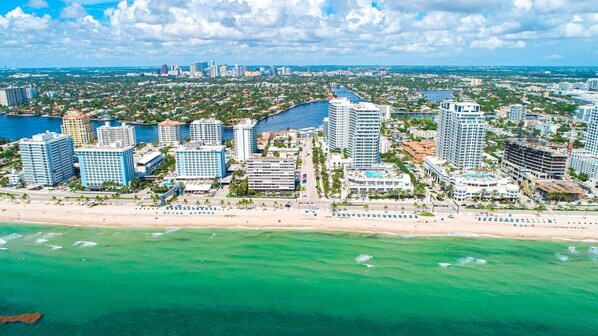 Un paisaje urbano costero con hoteles de gran altura, una playa y un puerto deportivo.
