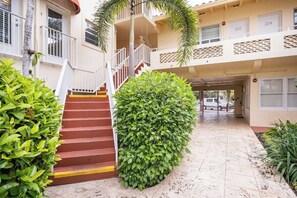 A multi-level building with a central staircase, a covered walkway, and a well-maintained garden area. - The Blue Octopus - 1br King Bed Condo (Fort Lauderdale)