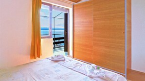 Un dormitorio con un armario de madera, una ventana con cortinas y una cama con toallas.