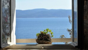 Una ventana con vista a un mar tranquilo y montañas lejanas.