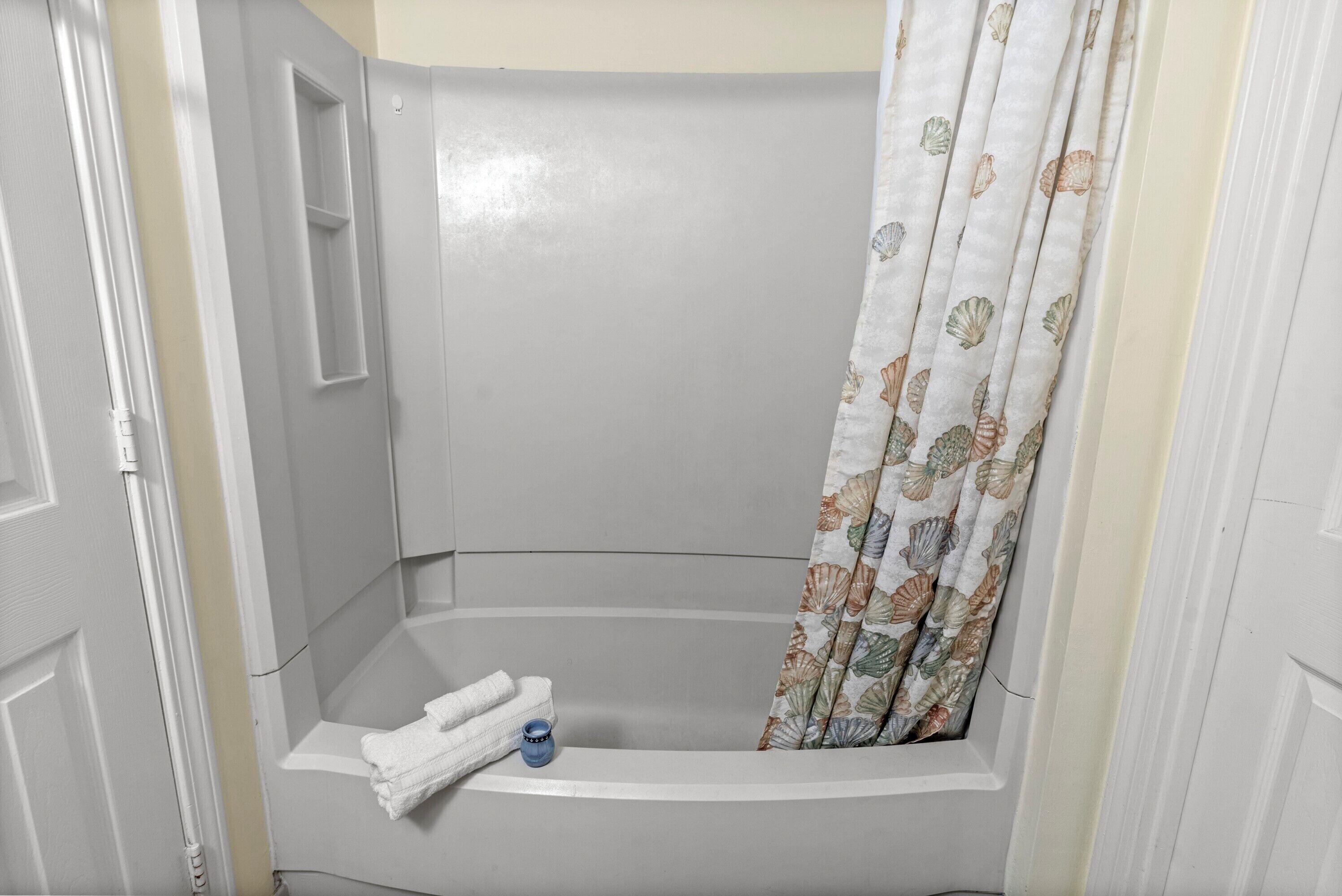 A bathroom with a shower, a towel rack, and a curtain.