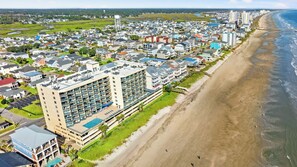 Uma área residencial costeira com um grande hotel, com várias varandas e uma piscina.