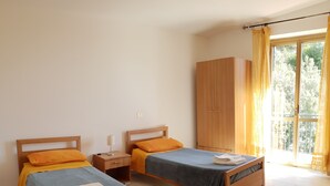 Een slaapkamer met twee houten bedden, een kledingkast en een raam met gordijnen.