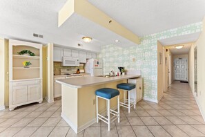 Une cuisine dotée d’un îlot central, de meubles blancs et d’un crédence décorée.