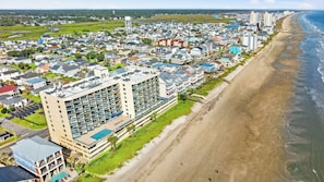 A coastal residential area with a large hotel featuring multiple balconies and a swimming pool.
