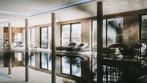 Amplio espacio interior con una gran piscina reflectante, zonas de estar y amplias ventanas que ofrecen vistas al exterior.