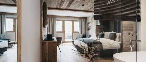 Ein modernes Schlafzimmer mit einem großen Bett, einer Duschkabine aus Glas und einer Holzbalkendecke.