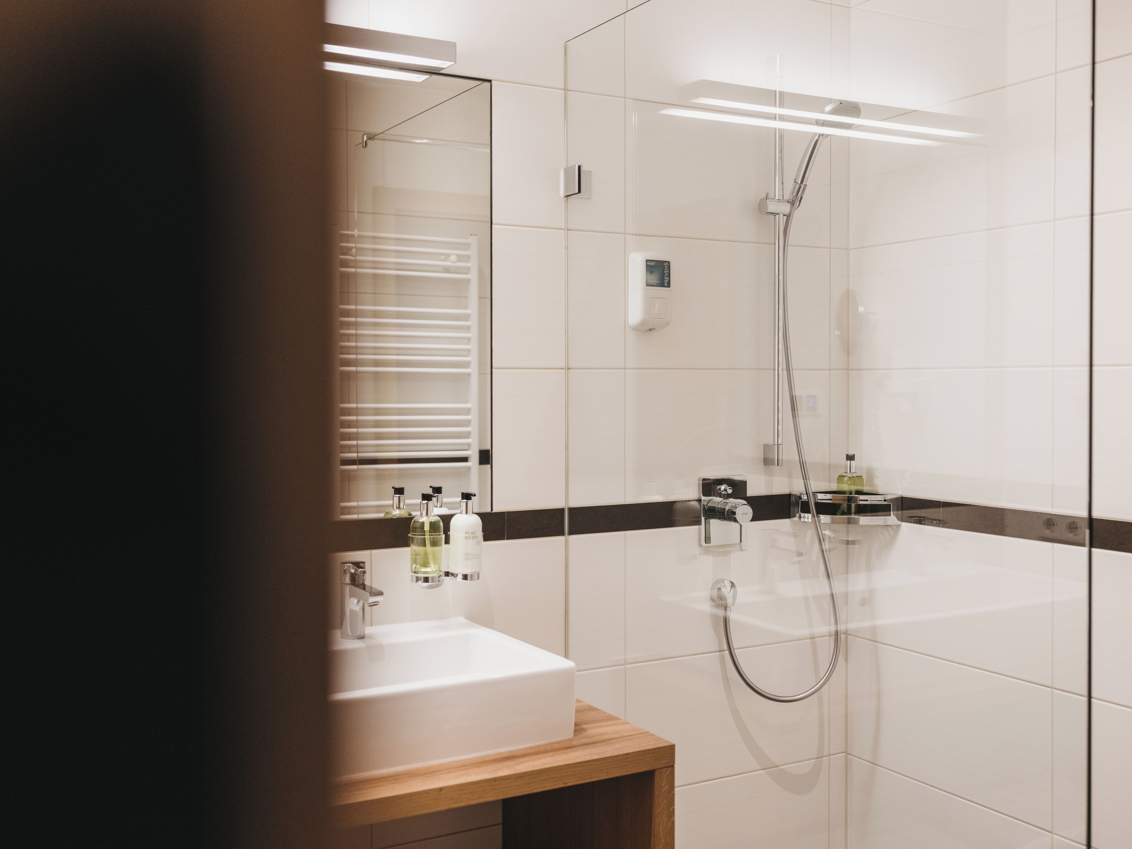 A modern bathroom with two sinks, a glass shower enclosure, and a mirror.