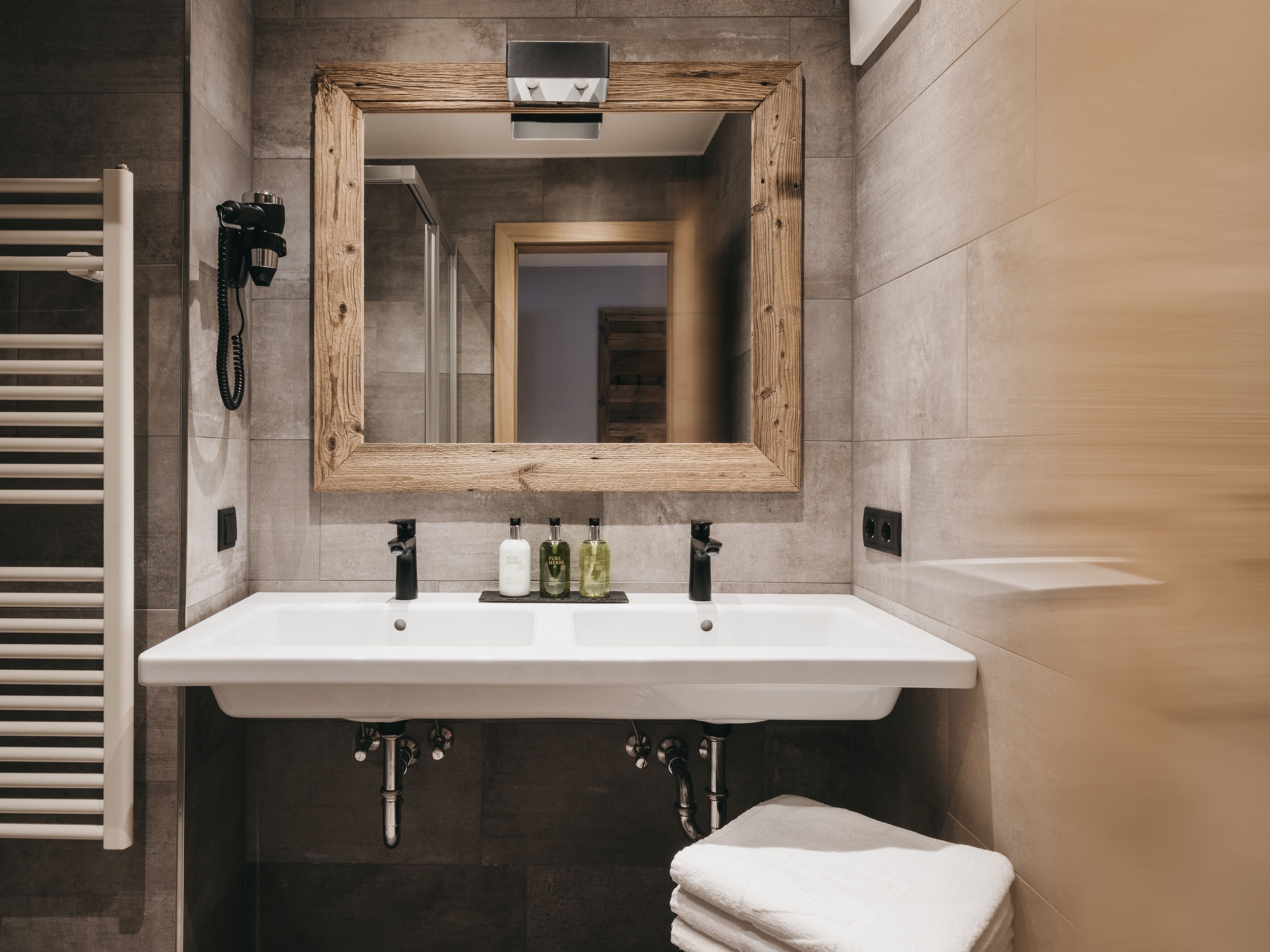 Une salle de bain moderne avec un grand miroir, un lavabo blanc et un porte-serviettes.