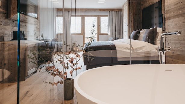 Un dormitorio moderno con una cama grande, una sala de estar separada y una bañera.