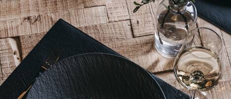 A dining table with a black plate, a glass of water, and a glass of wine.