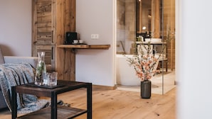 Una sala de estar moderna con piso de madera, un separador de vidrio y una cafetera sobre una estantería.