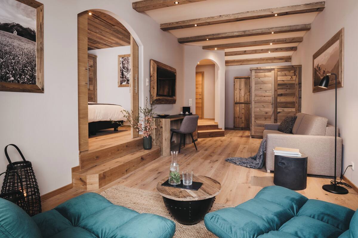 Een ruime woonkamer met een houten vloer, een bank, een bijzettafeltje en een bureau.