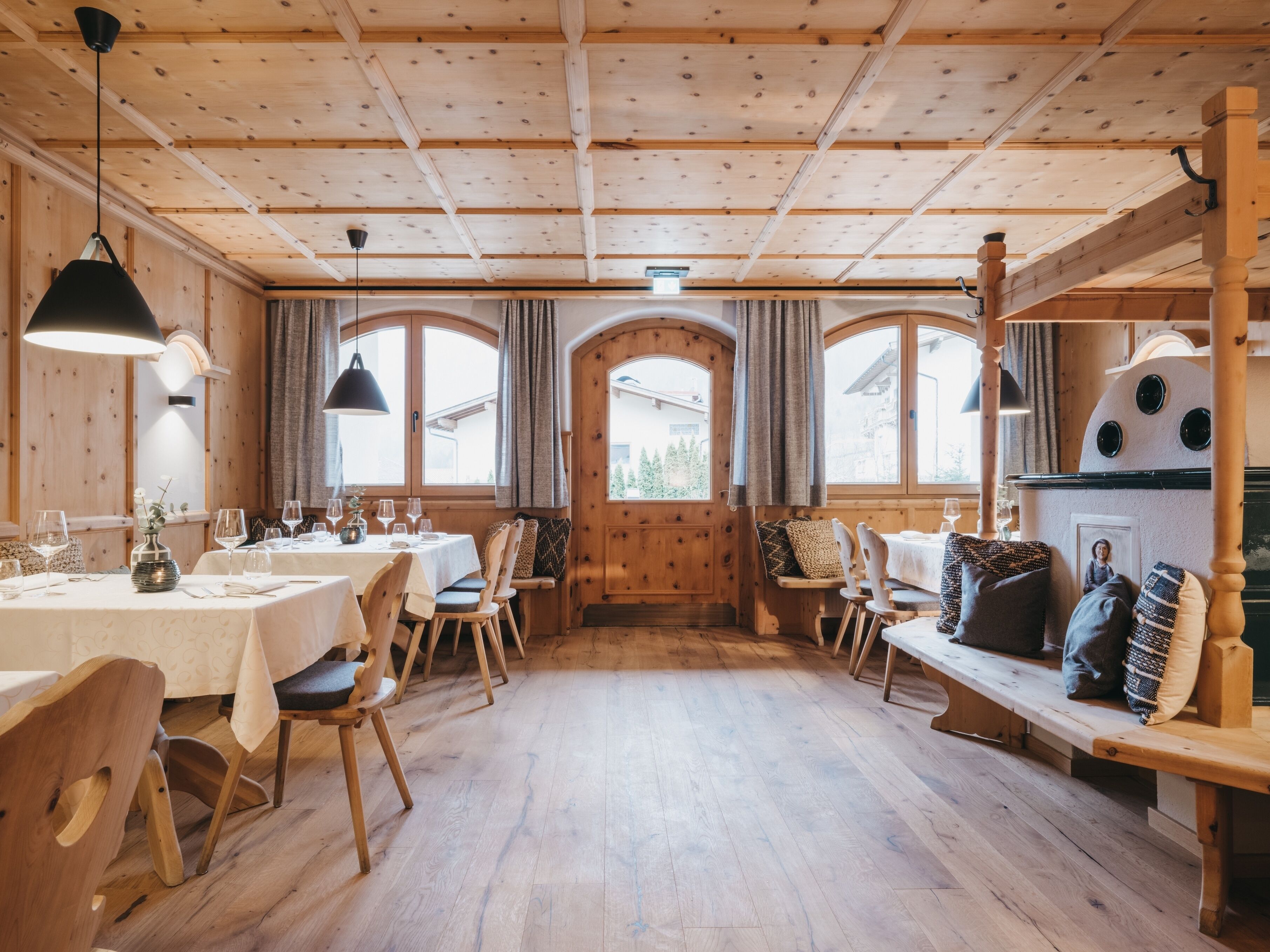 Un interior de madera con mesas, sillas, un banco y una chimenea.