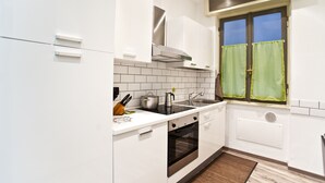 Une cuisine moderne avec des meubles blancs, des appareils en acier inoxydable et une fenêtre ornée de rideaux verts.