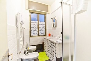 Ein kleines Badezimmer mit Toilette, Waschbecken und Fenster.