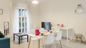 Een moderne woonkamer met een eethoek, een televisie en een boekenplank.