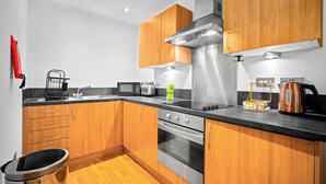 Una cocina moderna con armarios de madera, electrodomésticos de acero inoxidable y una encimera negra.