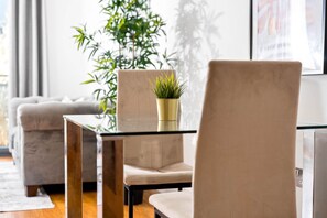 Un salon moderne avec une table basse en verre, un fauteuil beige et une plante en pot.