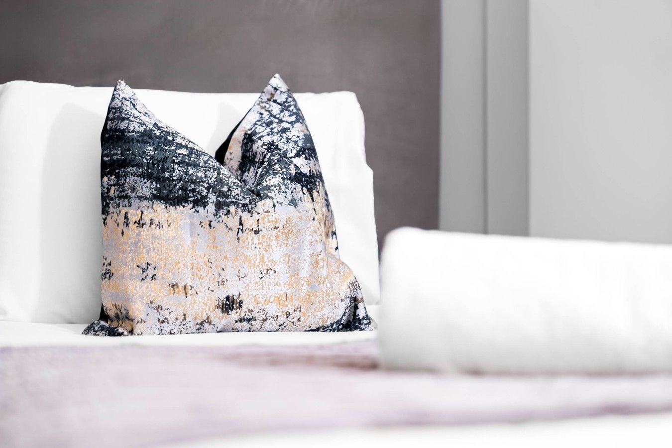 Un canapé blanc agrémenté d’un coussin texturé orné d’un motif abstrait en noir et blanc.