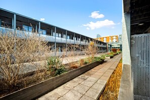 A modern building with a covered walkway and a garden area. - Arcadian Apartment - Secure Parking - Balcony (West Midlands)