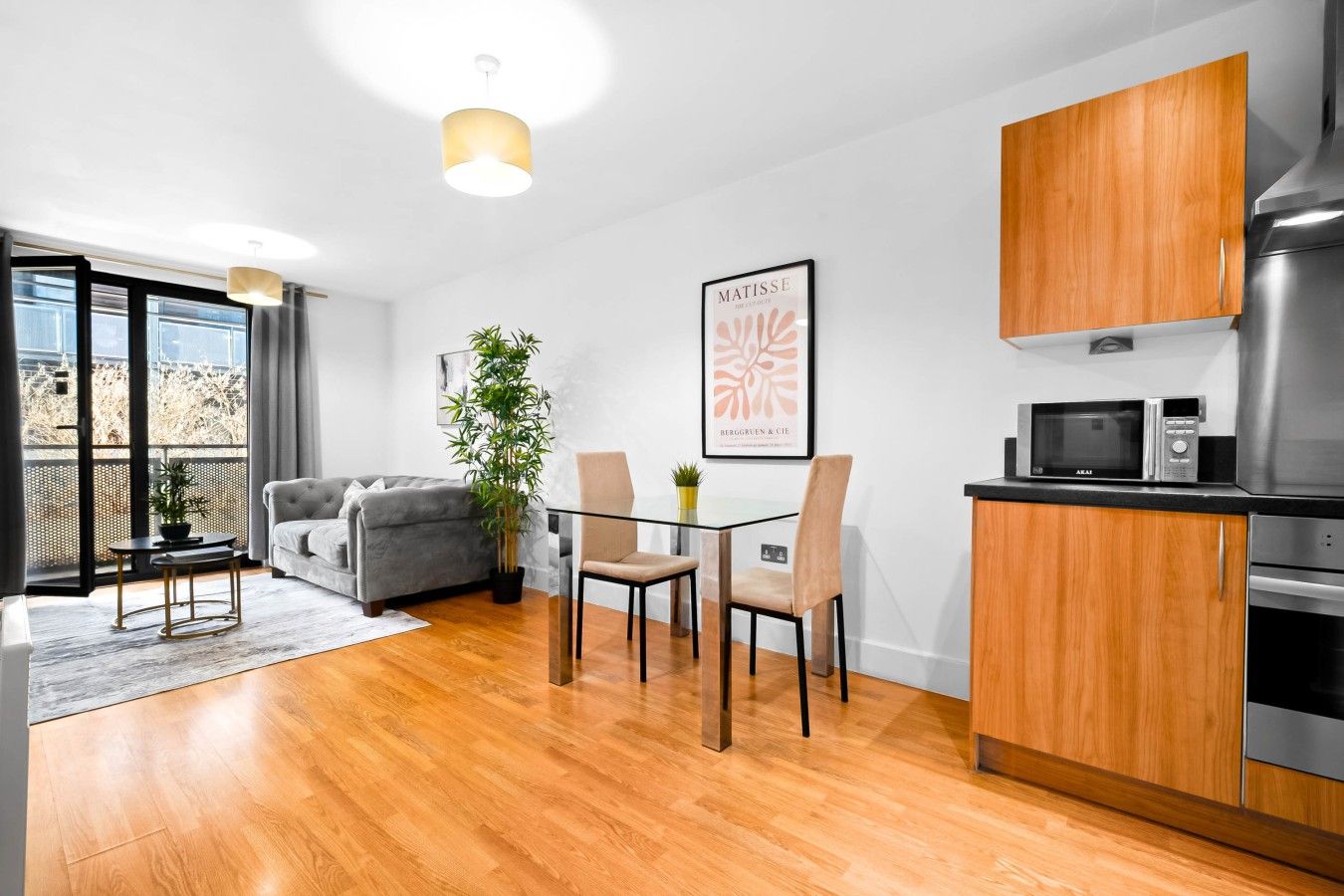 Un apartamento moderno con comedor, sofá, cocina equipada con microondas y un ventanal grande.