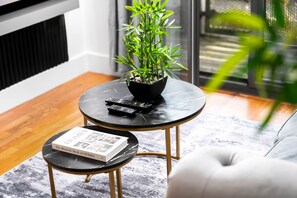 Un salon moderne avec une table basse en marbre noir, une petite plante en pot, un livre et une télécommande.