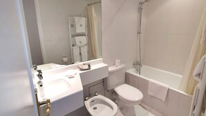 A modern bathroom with a bathtub, toilet, bidet, and a large mirror. - Appart'hotel Le Saint Antoine - Le Studio Confort en Centre Ville (Albi)