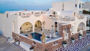 A white building with a pool, outdoor seating, and a view of the sea. - Merovigliosso Budget Studio ground floor (Thira - Santorini)