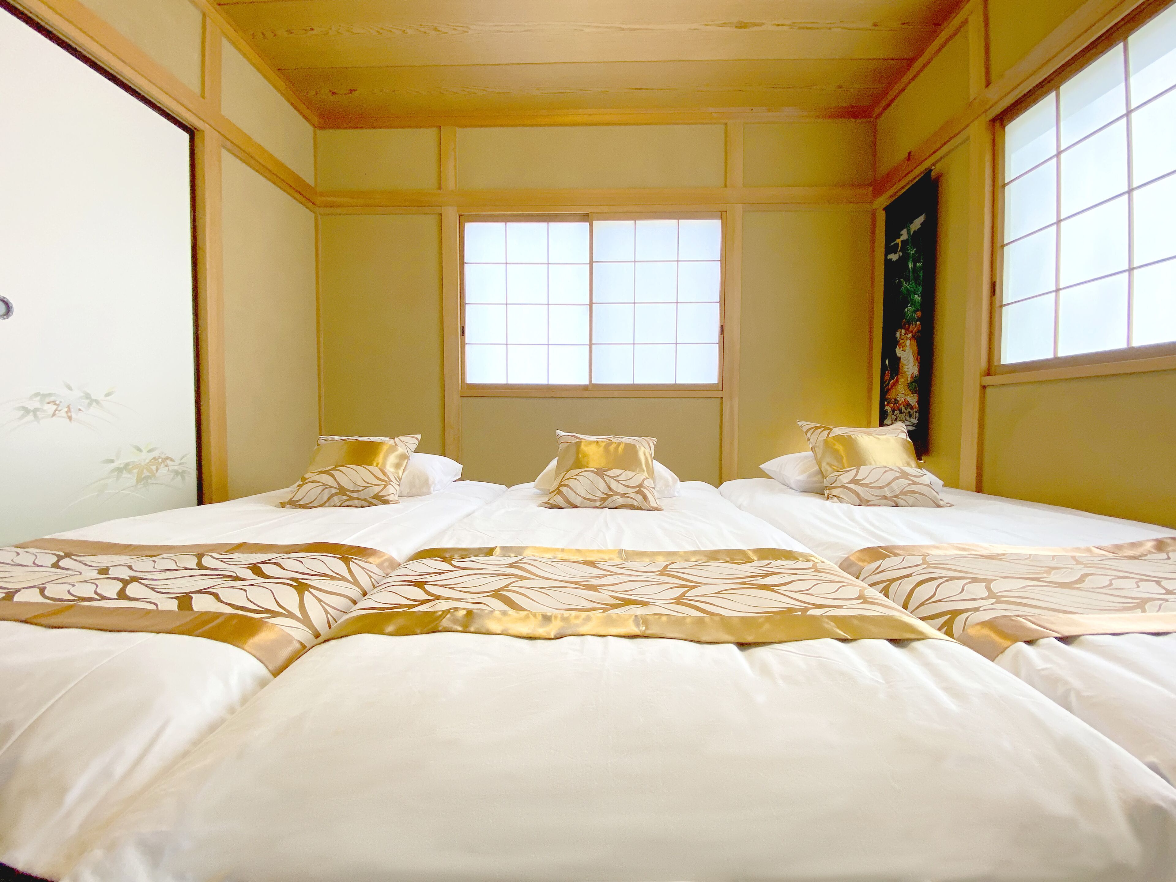 A hotel room with a large bed, a window, and a painting on the wall.