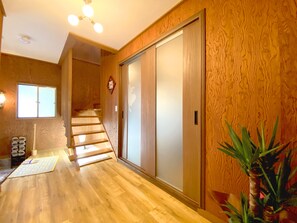 A wooden interior with a staircase, a sliding door, and a potted plant.
