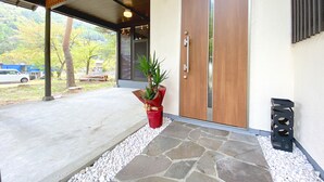 Una entrada moderna de edificio con un sendero de piedra, una puerta de madera y una planta en maceta.