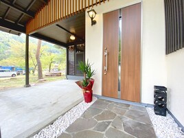Una entrada moderna de edificio con un sendero de piedra, una puerta de madera y una planta en maceta.