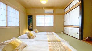 Una habitación tradicional japonesa con suelo de tatami, una pantalla shoji y una cama futón.