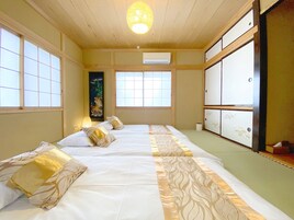 Una habitación tradicional japonesa con suelo de tatami, una pantalla shoji y una cama futón.