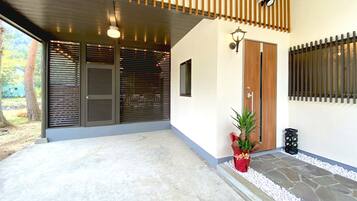 Ingresso moderno di un edificio con un portico coperto, una pianta in vaso e un vialetto in pietra che conduce alla porta.