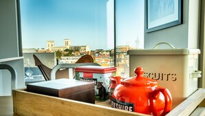 A wooden tray with a red Yorkshire Biscuit tin, a white container, and a brown box on a table by a window with a city view. - Cityscape @ Ryedale House -  a family break that sleeps 4 guests  in 2 bedrooms (York)