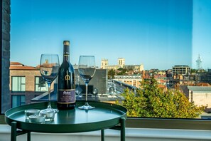 A table with a bottle of wine and two glasses on a balcony overlooking a cityscape. - Cityscape @ Ryedale House -  a family break that sleeps 4 guests  in 2 bedrooms (York)