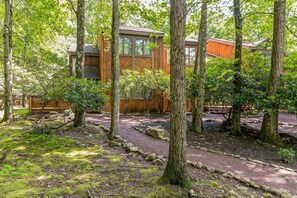 Escape to a serene forest retreat with a cozy cabin nestled among tall trees, offering stunning views of the surrounding woodland.
