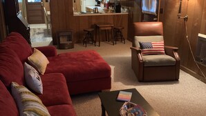 Ein Wohnzimmer mit einem roten Ecksofa, einem Holzesstisch und einer Küche im Hintergrund.