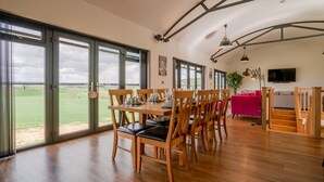 A spacious dining area with large windows, wooden furniture, and a view of the outdoors. - Lower Lodge Barn - sleeps 8 guests  in 4 bedrooms (Alcester)