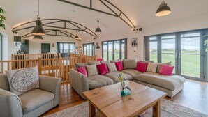 A spacious living area with a large sectional sofa, a wooden coffee table, and multiple hanging pendant lights. - Lower Lodge Barn - sleeps 8 guests  in 4 bedrooms (Alcester)