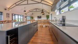 A modern kitchen with a central island, wooden flooring, and pendant lighting. - Lower Lodge Barn - sleeps 8 guests  in 4 bedrooms (Alcester)